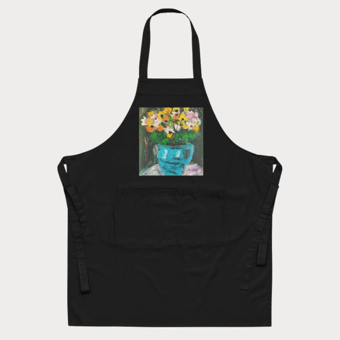 Gros plan sur le tablier de cuisine artistique noir, orné d’un motif floral coloré et moderne.