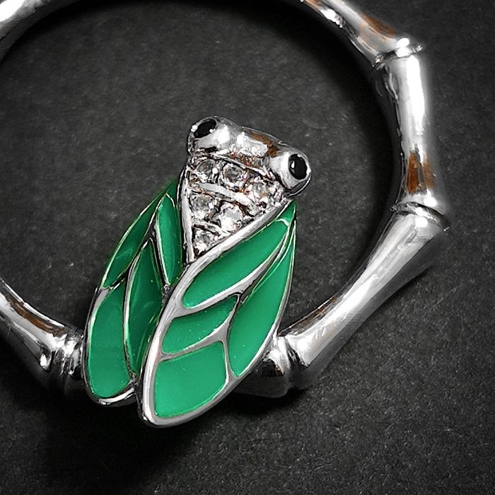 Détail du pendentif cigale en argent 925, ailes vertes émaillées et brillants scintillants.