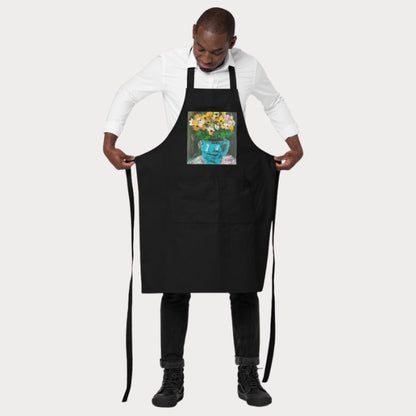Tablier de cuisine artistique ajustable noir mettant en valeur un bouquet fleuri dans un vase turquoise.