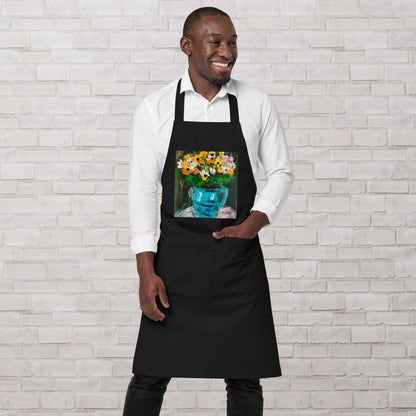 Tablier de cuisine artistique noir avec motif bouquet fleuri porté par un homme souriant.